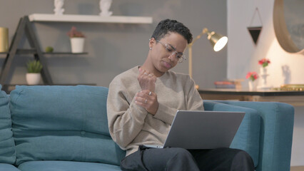 African Woman with Laptop having Wrist Pain on Sofa