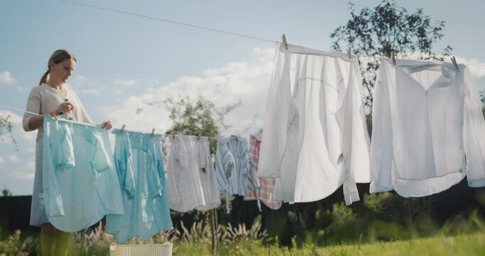Middle-aged woman hanging laundry on clothesline to dry