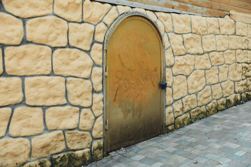 The stone wall of the old castle with closed large metal doors. Ancient gates. a gate on a brick wall.