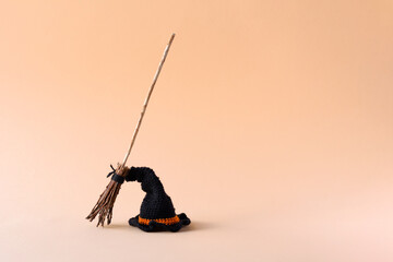 Fototapeta na wymiar Halloween concept. A black hat and a witch's broom on an orange background, front view, copy space