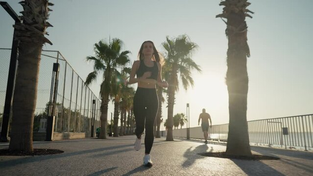 Young active woman jogging along beautiful beach. Running happy woman enjoying their summer morning workout. High quality 4k footage