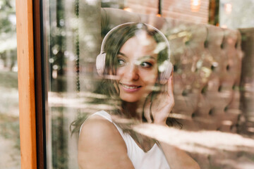 Portrait of a beautiful young woman with headphones, who listens to music while sitting in a street cafe.Enjoy the music, generation Z