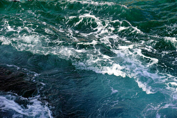 Abstractly foamy surface of dark blue sea water with white foamy waves