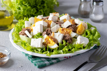 Salad with canned tuna, cucumber, boiled eggs and feta cheese, served on lettuce leaves with french mustard