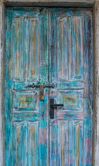 Colourful wooden doors on a brown house; blue painted texture entrance and door to an old colonial house; colourful door with a metal latch and padlock from a world heritage site 