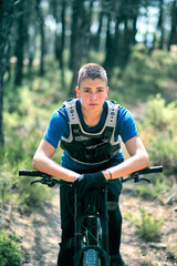 Teenager in forest with downhill bike.