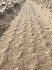 In the sand are grooves of a tire track