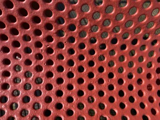 Red curved perforated metal sheet close up