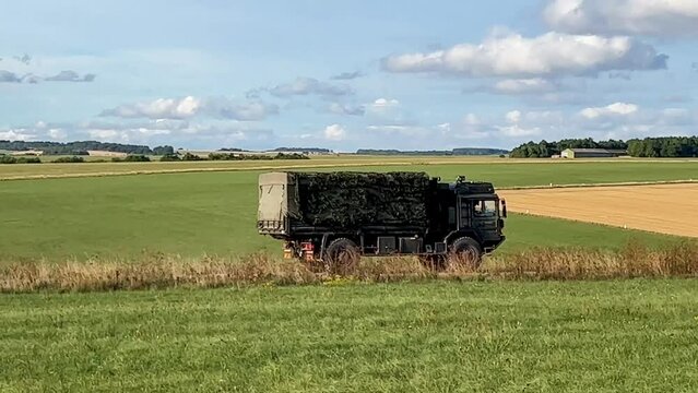 British army MAN HX60 SV 4x4 logistics lorry in action on a military exercise, blue sky with white cloud 