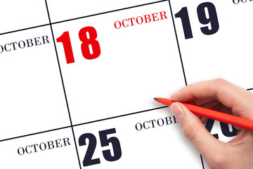 A hand holding a red pen and pointing on the calendar date October 18. Red calendar date, copy space, mockup.