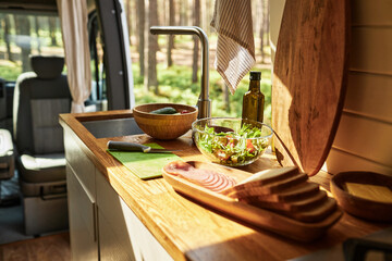 Close-up of kitchen table with salad in bowl and wooden board with bread in motorhome