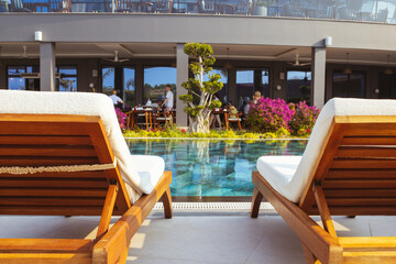 Beautiful luxury umbrella and chair around outdoor swimming pool in hotel and resort with coconut palm tree on blue sky 