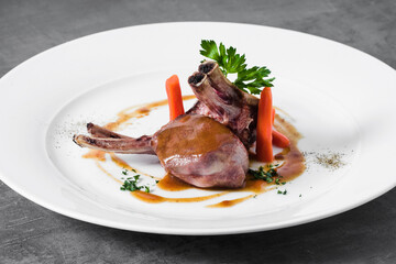 lamb in sauce with baby carrots on a plate. a dish in a restaurant on a dark background