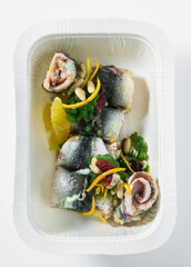sardine rolls with parsley caviar. and citrus. high restaurant cuisine in a plastic takeout container