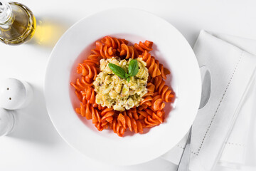 fusilli pasta in tomato sauce with rabbit sauce and fresh basil on white