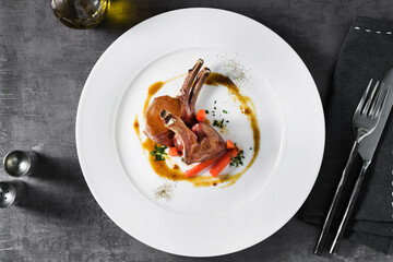 lamb in sauce with baby carrots on a plate. a dish in a restaurant on a dark background