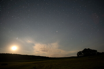 Beautiful panorama of bright blue sky with shining stars and milkyway over dark mountains landscape at night