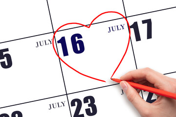 A woman's hand drawing a red heart shape on the calendar date of 16 July. Heart as a symbol of love.
