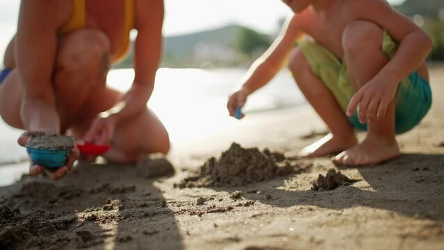 Mother and son play with toys on the beach in the sand. Happy seven times on summer vacation by the ocean. High quality 4k footage