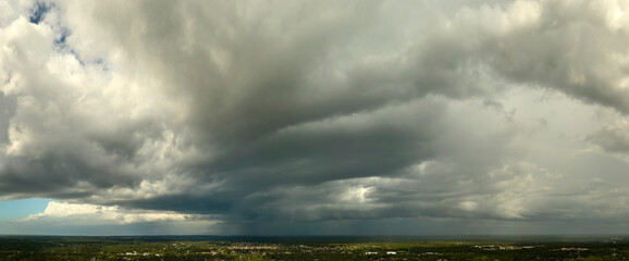 Landscape of dark ominous clouds forming on stormy sky before heavy thunderstorm over rural town area