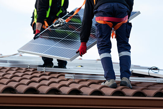 Dos t&eacute;cnicos instalando placas solares en una vivienda.