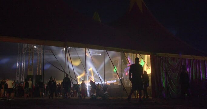 Silhouettes of visitors to a musical event under the tent of dance floor at night. CZ, Milovice, Let it Roll