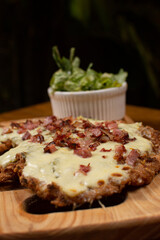 Milanese with topping. Milanesa covered with arugula, tomatoes, cheese. Breaded meat. Italian food. Fried meat. Beef, chicken meat, pork meat.