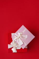 Soft Selective focus Top view of two gift boxes with satin light ribbon on red background. Pink gift for Christmas, New Year or romantic Valentine's Day. Copy space for text. Vertical photo