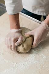 male chef's hands knead the dough for baking bread