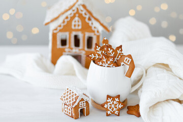 Hot winter drink in a white mug: cozy home composition with homemade gingerbread cookies, candy...