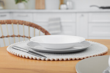 Stylish ceramic plates and cutlery on wooden table in kitchen