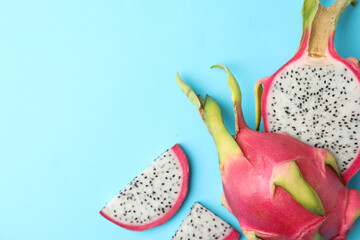 Delicious cut dragon fruit (pitahaya) on light blue background, flat lay. Space for text