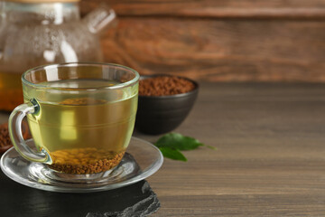 Freshly made buckwheat tea in glass cup on wooden table. Space for text