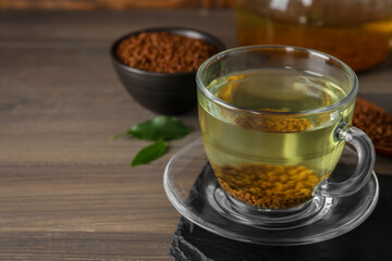 Freshly made buckwheat tea in glass cup on wooden table. Space for text