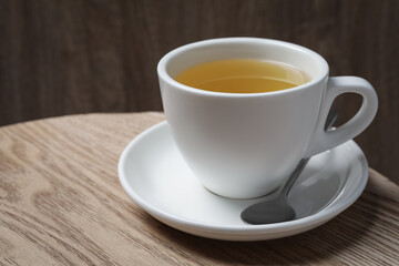 Cup of aromatic buckwheat tea and spoon on wooden table