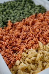 Background texture of tricolor fusilli pasta for traditional Italian and Mediterranean cuisine in a close up full frame view