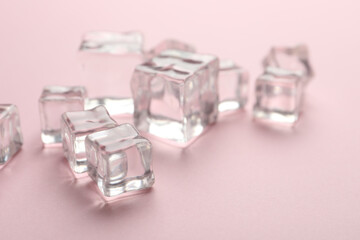 Crystal clear ice cubes on pink background, closeup