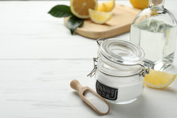 Baking soda, vinegar and cut lemons on white wooden table. Space for text