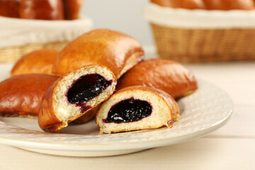 Delicious baked patties with jam on white wooden table, closeup
