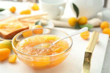 Delicious kumquat jam in glass bowl on white tray, closeup
