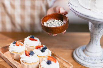 Pastry chef confectioner young caucasian woman decorate sweet balls candy cake on kitchen table. Cakes cupcakes and sweet dessert