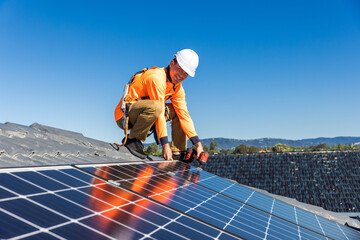 Solar panel technician with drill installing solar panels