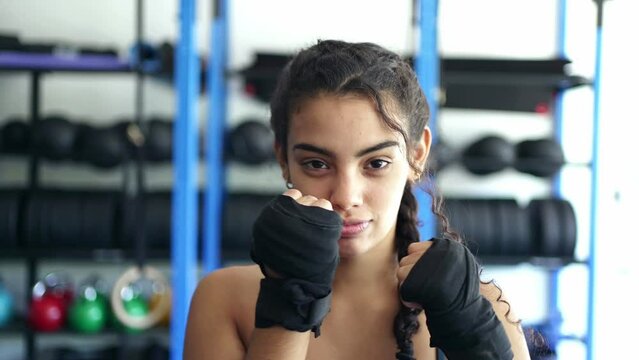 Young beautiful fit woman with boxing tapes on hands as she prepares for a kickboxing workout at fitness gym.