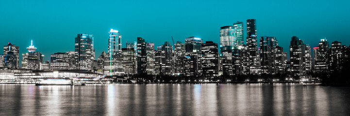 Fototapeta na wymiar Vancouver city skyline at night with seawater reflections in Vancouver Harbor, British Columbia, Canada. Monochromatic nightscape of metropolitan downtown buildings.