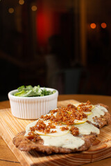 Milanese with topping. Milanesa covered with arugula, tomatoes, cheese. Breaded meat. Italian food. Fried meat. Beef, chicken meat, pork meat.