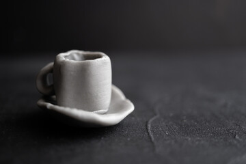 taza de café con platito hecha de plastilina gris con fondo  negro
