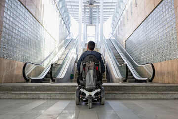 Person with disability on electric wheelchair stopping at the bottom of inaccessible staircase,...