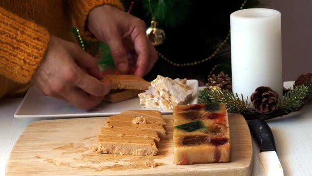 A woman puts pieces of traditional Spanish turron on a plate