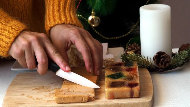 A woman cuts soft almond turron into pieces with a knife.