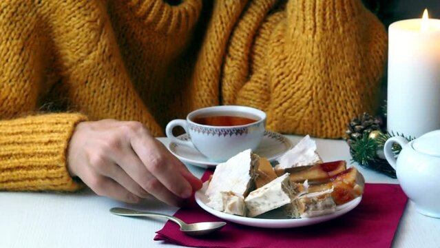 A woman with her hand turns a plate on which there are pieces of a different type of traditional Spanish Christmas dessert - Turron.